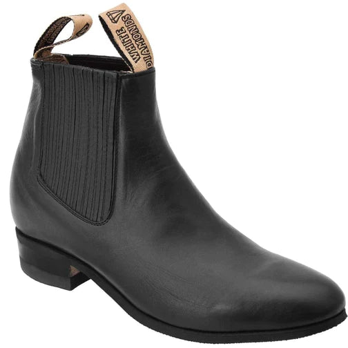 A black charro ankle boot for men with a pull tab and side elastic inserts, featuring a square toe and a low traditional heel.