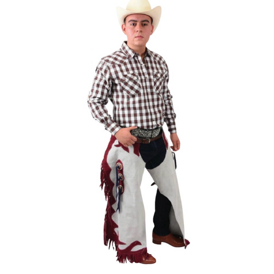 A man wearing a cowboy hat and a plaid shirt, adorned with a traditional leather cowboy chaps featuring fringes and decorative details.